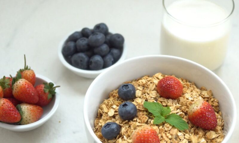 prikaz pahuljica, bobičastog voća, jagoda i i mleka na stolu.