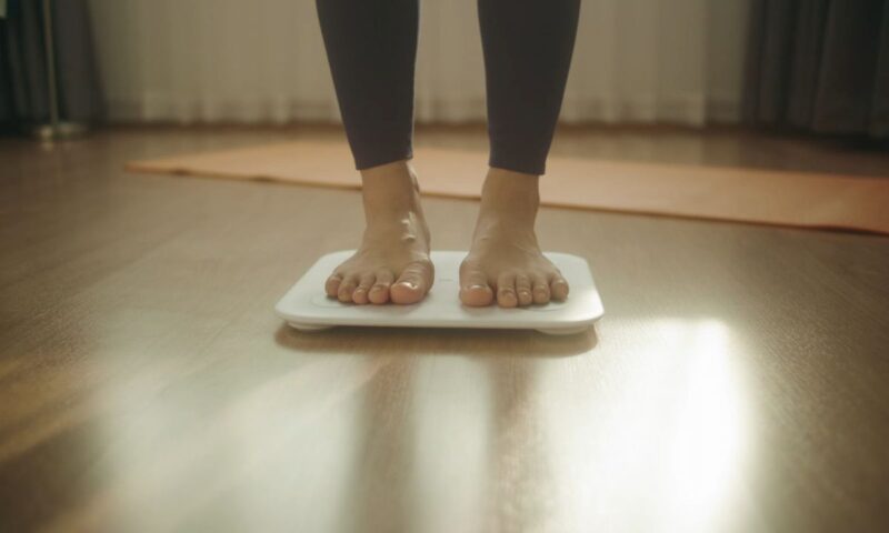 devojka stoji na vagi za merenje